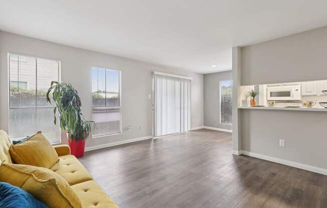 A living room with a yellow sofa and a kitchen area in the background.