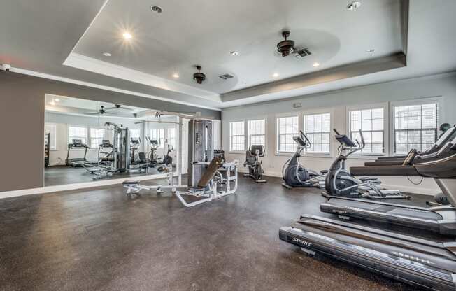 the gym has treadmills and other exercise equipment and windows