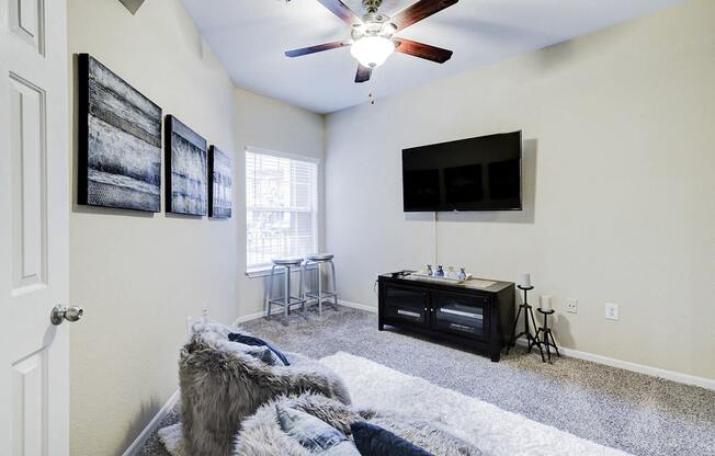 a living room with a ceiling fan and a tv