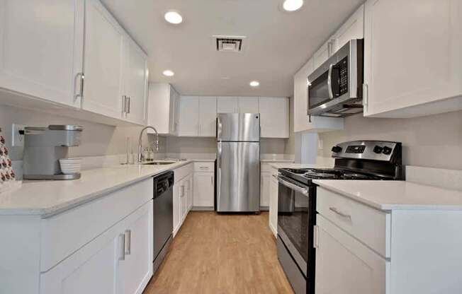 A kitchen with white cabinets and a stainless steel refrigerator.