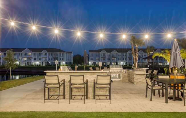 a patio with tables and chairs and a fire pit at night