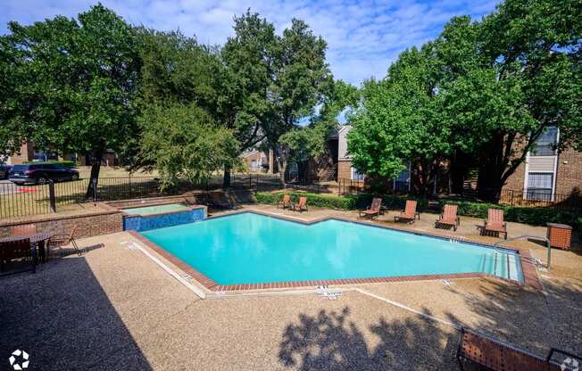 A swimming pool surrounded by trees and a fence.