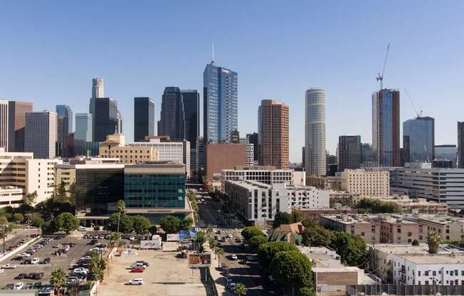 A cityscape with a mix of modern and older buildings, a parking lot in the foreground, and a clear blue sky.