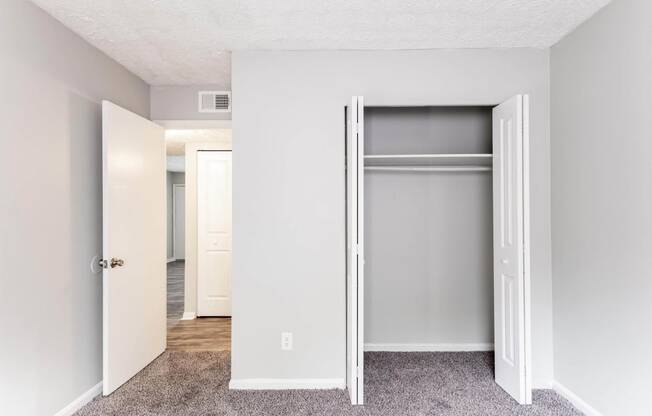 an empty bedroom with an open closet door