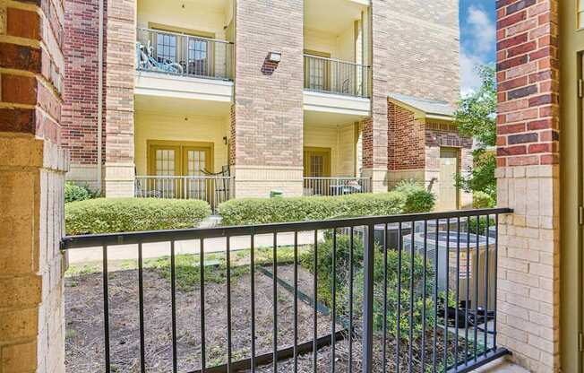 A view of a courtyard from a doorway with a black metal fence.