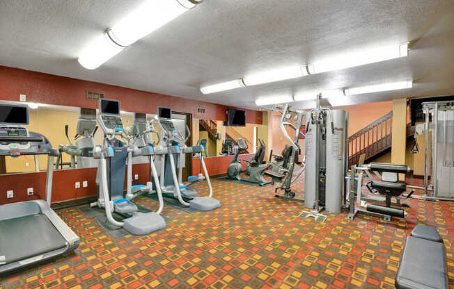 A gym with a variety of equipment including treadmills, weights, and exercise machines.