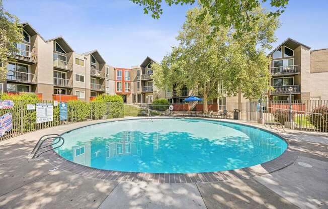 A round swimming pool in the middle of a courtyard surrounded by apartment buildings.