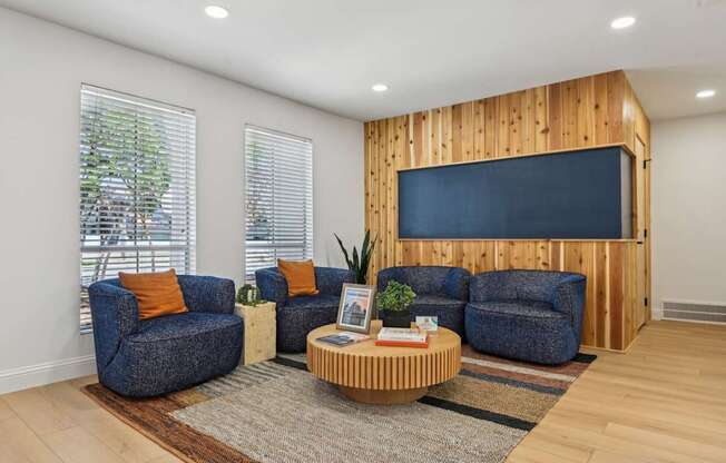 A living room with a blue couch, a wooden coffee table, and a flat screen TV mounted on a wooden wall.