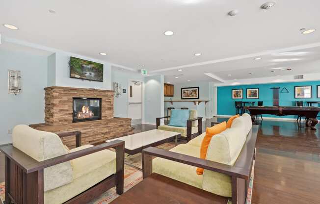 a living room with couches a fireplace and a pool table