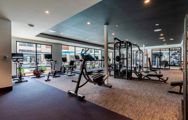 a gym with exercise equipment and large windows  at Century West Pryor, Lee's Summit, MO