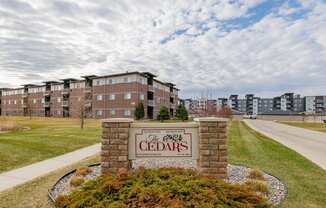 The Cedars apartment complex is surrounded by a well-maintained lawn and a clear sky.