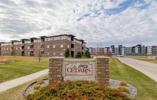 The Cedars apartment complex is surrounded by a well-maintained lawn and a clear sky.