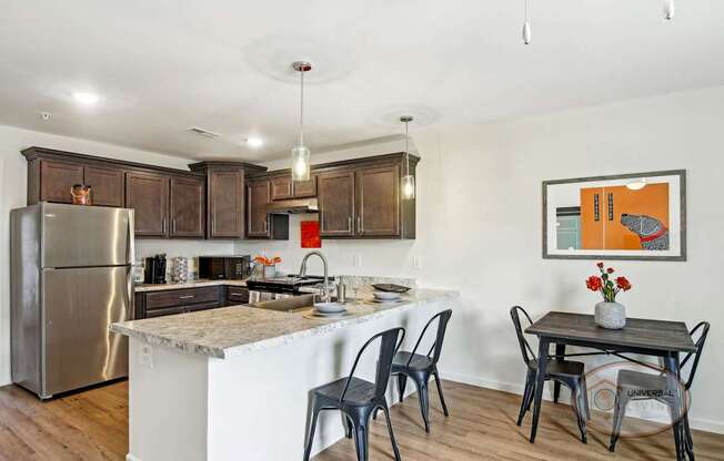 A kitchen with quartz counters, dark cabinets, stainless steel appliances, and a table and chairs.