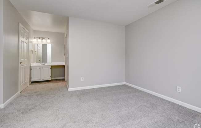 a bedroom with white walls and carpet and a bathroom