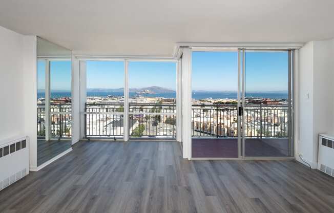 an open living room with hardwood floors and a balcony with a view of the city