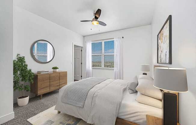 A bedroom with a bed, a ceiling fan, and a window with blinds at Trade Winds Apartment Homes, Elkhorn, Nebraska