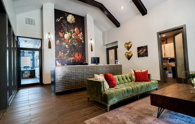 a living room with a green couch and a painting on the wall