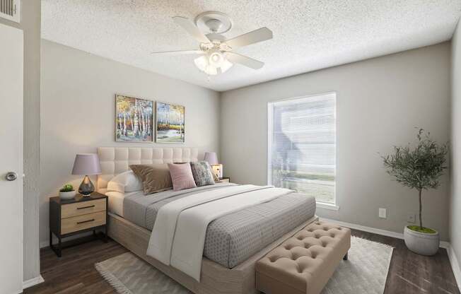 A bedroom with a large bed, a ceiling fan, and a potted plant.