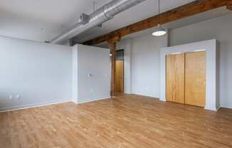 an empty living room with wood floors and a door to a closet