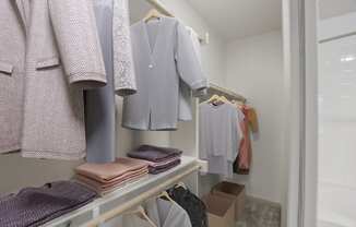 a walk in closet with a rack of clothes and a mirror