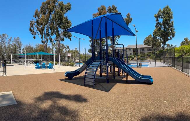 a playground with a swing set and a blue pavilion