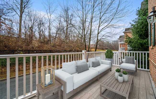 A wooden deck with a white couch and pillows.