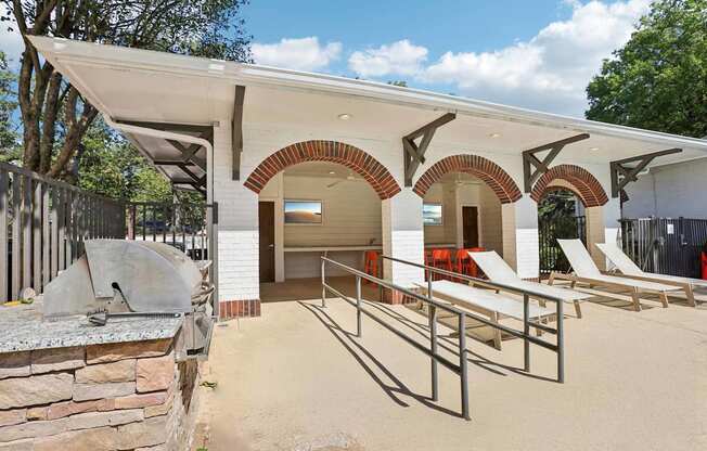 A building with a white roof and arched openings has a concrete wall in front of it.