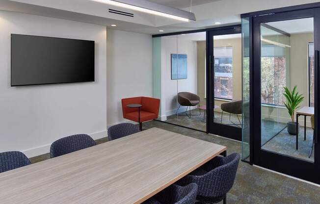 A conference room with a long table, chairs, and a television on the wall.