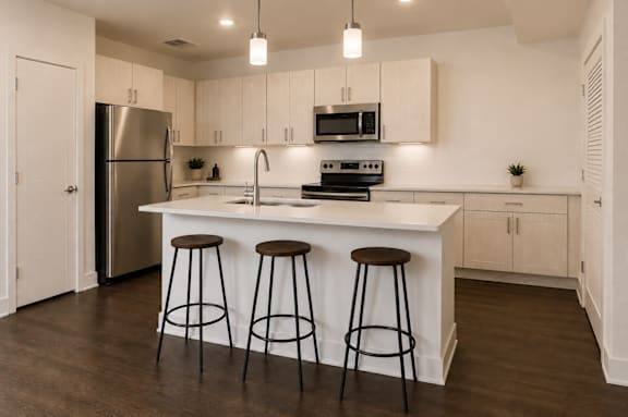 A kitchen with white cabinets and a white island with two stools.