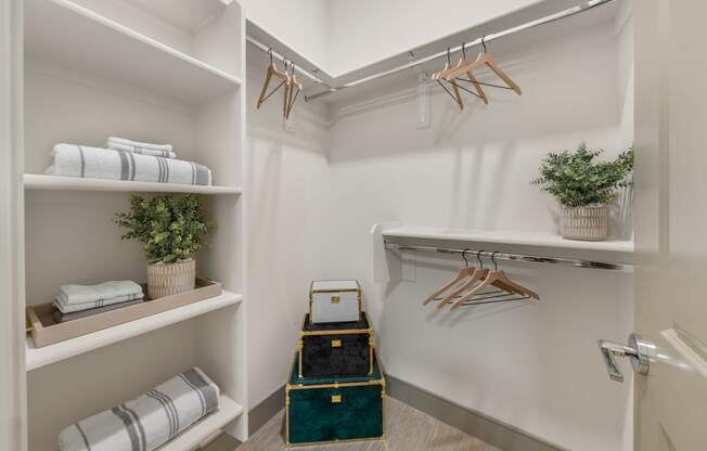 a walk in closet with folded towels and a luggage cart