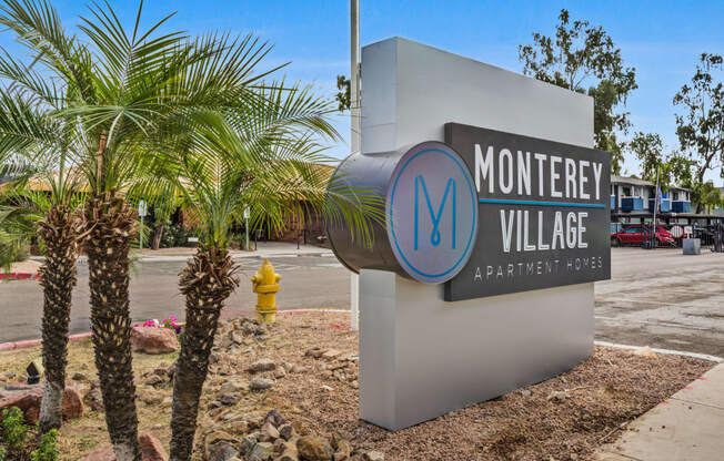 a sign for monterey village with a yellow fire hydrant in the background