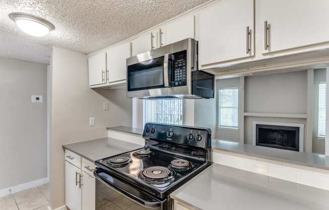a kitchen with white cabinets and a stove and microwave
