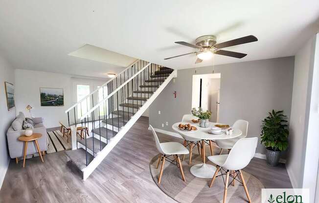 A dining room with a table set for four and a staircase.