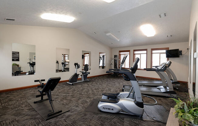 a gym with treadmills and other exercise equipment in a large room with windows