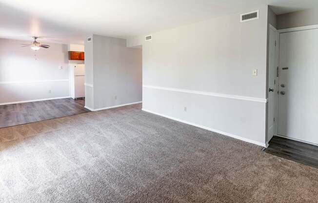 an empty living room with carpet and a door to a bedroom