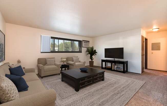 Bismarck, ND Rosser Apartments. A living room with couches, a coffee table, and a tv. A long window fills the room with bright natural light