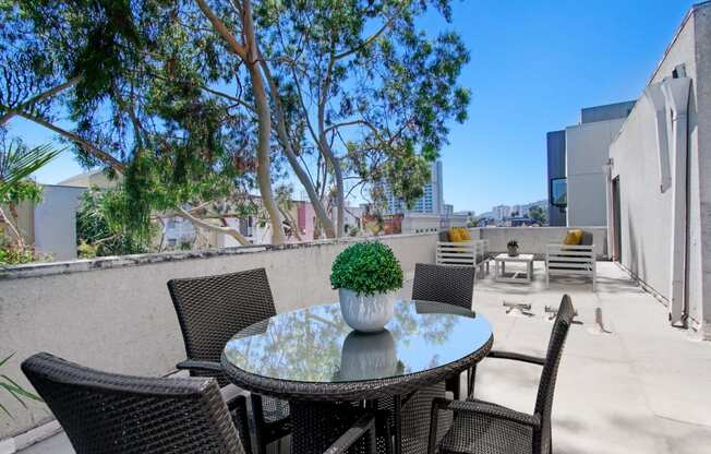 a patio with a table and chairs and trees in the background