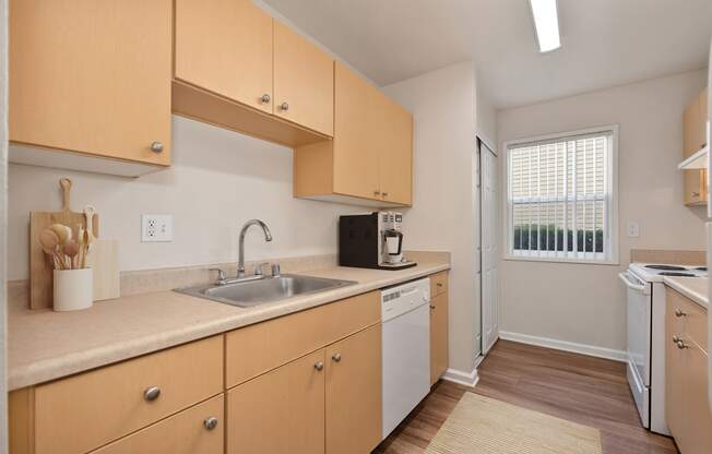 a kitchen with wooden cabinets and a sink and a window at Vineyard Terrace Apartments, California, 94558