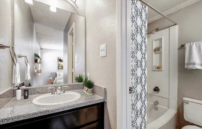 A bathroom with a sink, mirror, and shower.