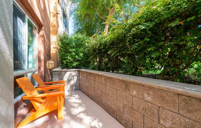 a small patio with orange chairs and a brick wall