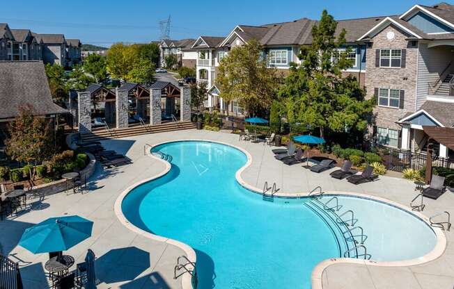 an aerial view of a swimming pool with umbrellas in front of a house