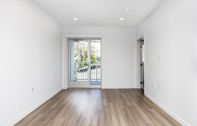 a living room with white walls and a door to a balcony