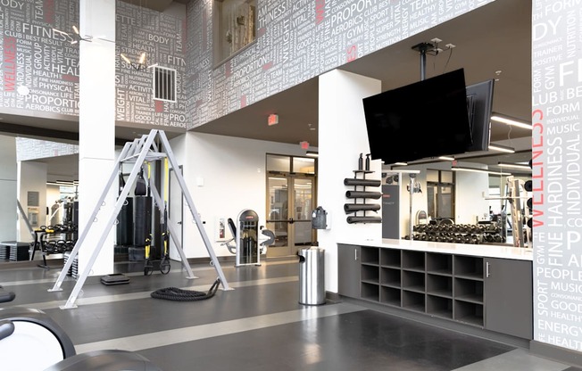 a gym with a tv on the wall and a counter with weights