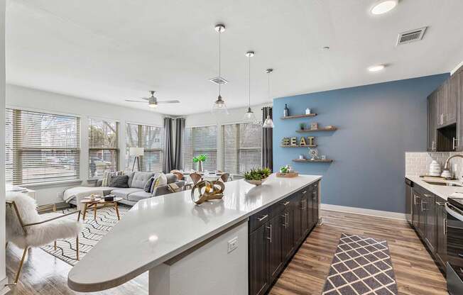 A modern kitchen with a white island and a dining area with a white chair.
