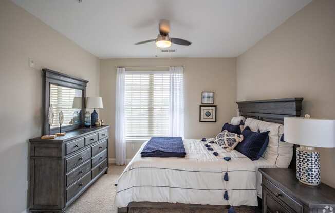 a bedroom with a bed and dresser and a ceiling fan