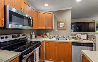 A kitchen with wooden cabinets and a stainless steel dishwasher.