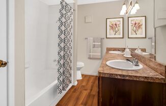 A bathroom with a marble countertop and a shower with a patterned curtain.