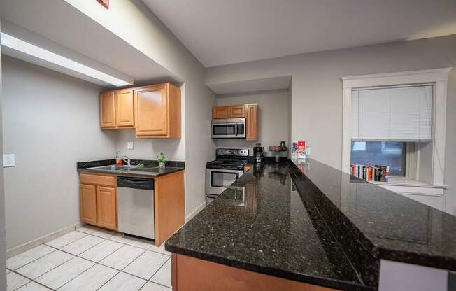 A kitchen with black granite countertops and wooden cabinets.