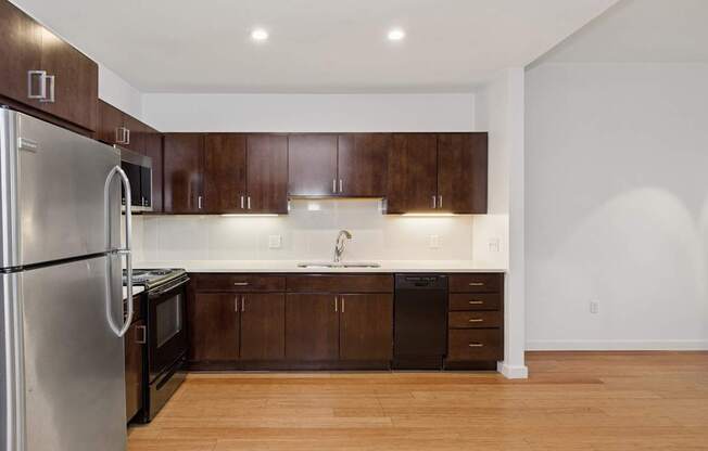 A kitchen with wooden cabinets and a stainless steel refrigerator.