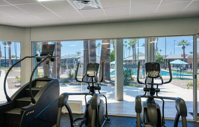 a gym with cardio machines and a view of a pool at Presidio Palms Apartments, Arizona, 85701